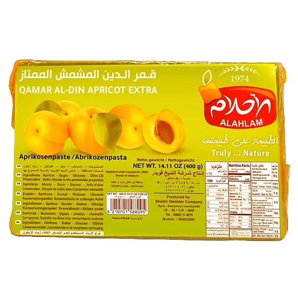 A package of Alahlam Qamar Al-Din Apricot Extra spread, featuring a bright yellow-green wrapper with Arabic and English text, a red Alahlam logo, and a barcode, set against a solid black background.