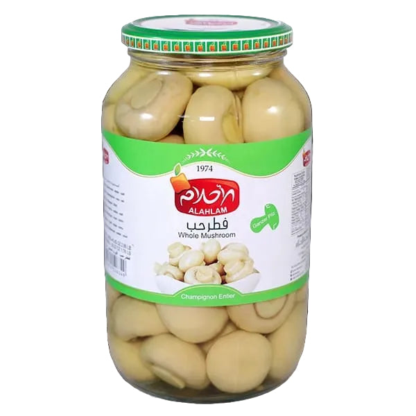 A glass jar of Alahlam Whole Mushroom  on a solid black background. The jar contains whole mushrooms and features a green and white label with the red Alahlam brand logo.