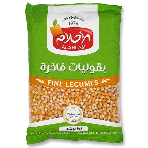 A green bag of Alahlam Fine Legumes popcorn kernels, featuring a prominent red and white Alahlam logo and a clear window showing the golden-yellow corn kernels inside.